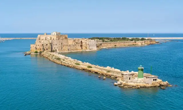 Fortezza Aragonese e faro verde a Brindisi, dove il mare azzurro incontra la storia.