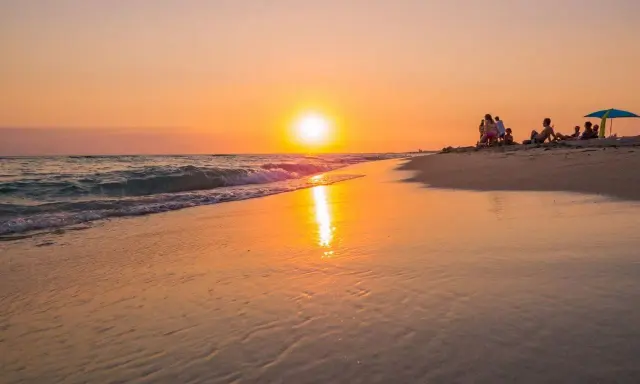 Tramonto dorato sulla spiaggia di Ugento, Salento. Famiglie rilassate sulla sabbia mentre il sole si specchia sul mare calmo.