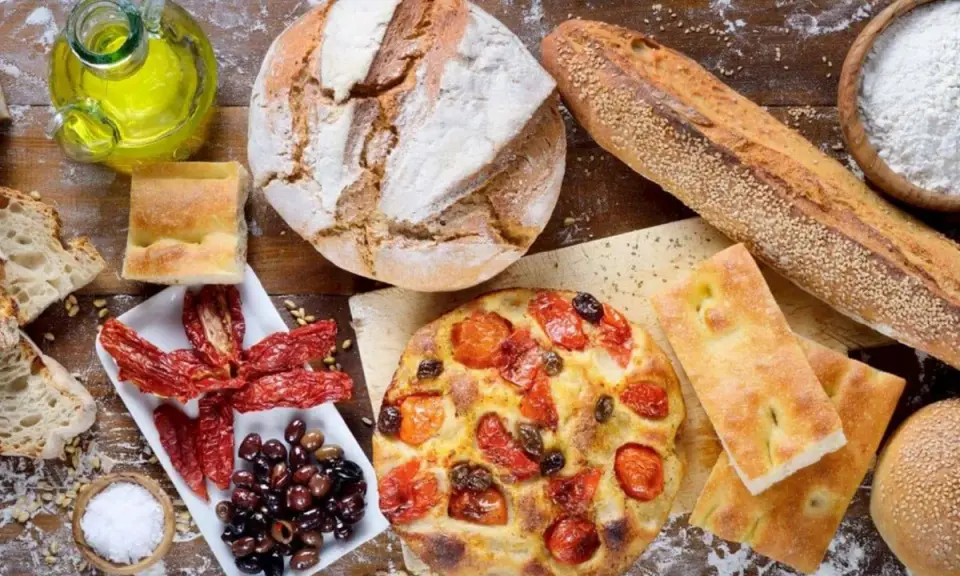 Pane, focaccia, pomodori secchi e olive: un assaggio dei piatti tipici pugliesi, con olio d'oliva e sale.