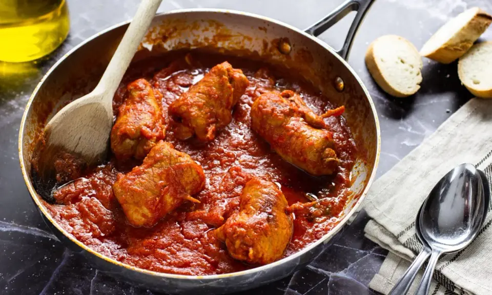 Braciola pugliese in padella con sugo rosso, pronte per essere gustate con pane fresco.