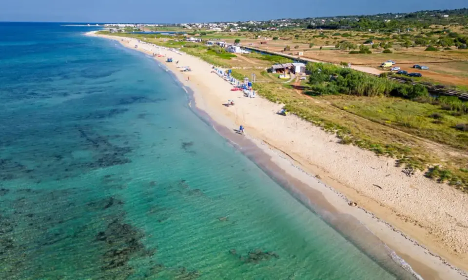 Spiaggia di Torre Vado, Pescoluse, con acque cristalline e sabbia dorata. Un luogo ideale per rilassarsi e godersi il sole.