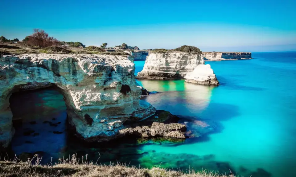 Scogliere bianche e mare turchese, un sogno per i mete puglia estate. L'arco naturale invita a scoprire le acque cristalline.