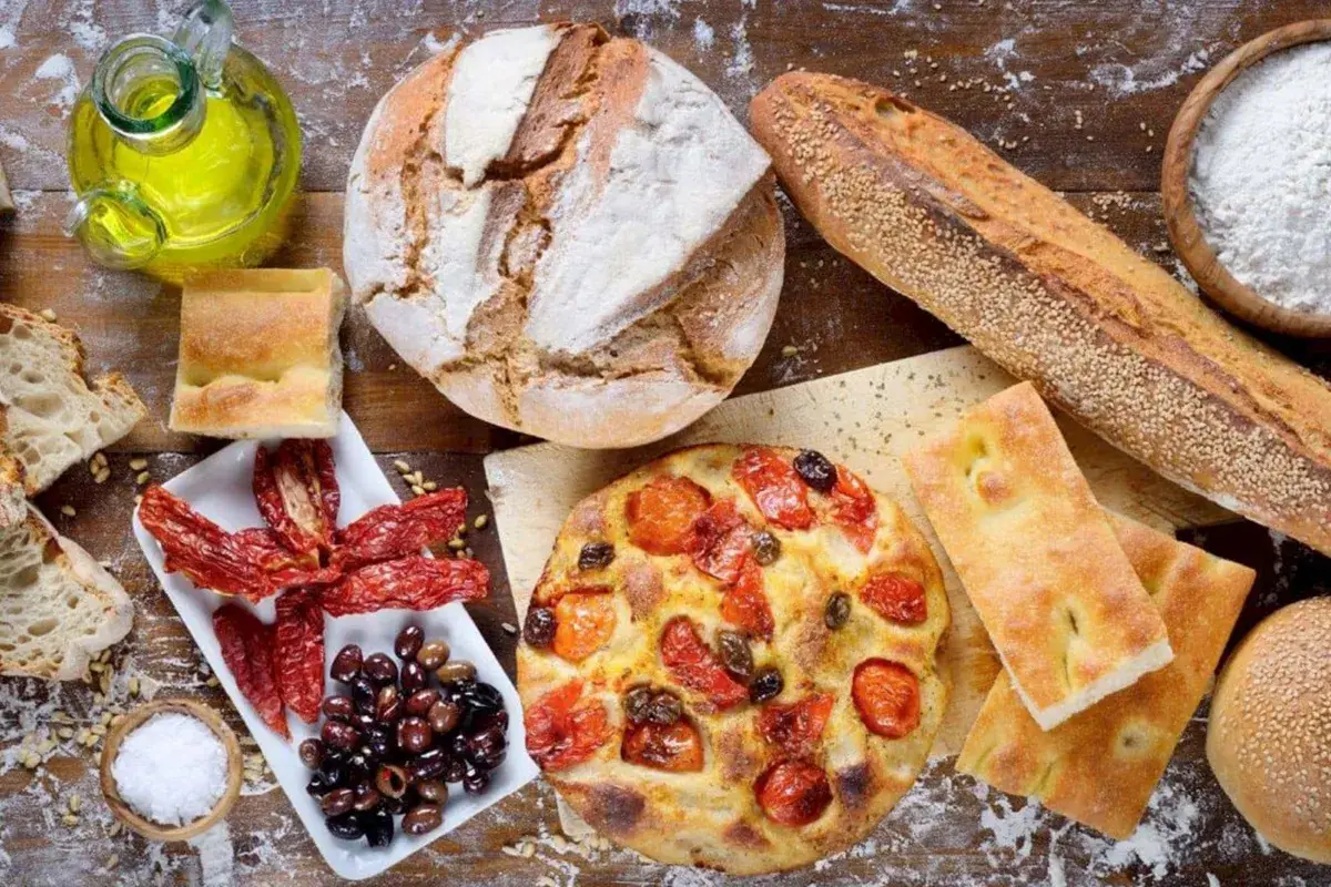 Pane, focaccia, pomodori secchi e olive: un assaggio dei piatti tipici pugliesi, con olio d'oliva e sale.