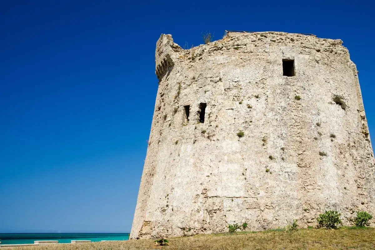 Antica torre mozza, con merli frastagliati, si erge contro un cielo blu intenso, testimone silenzioso di antiche storie.