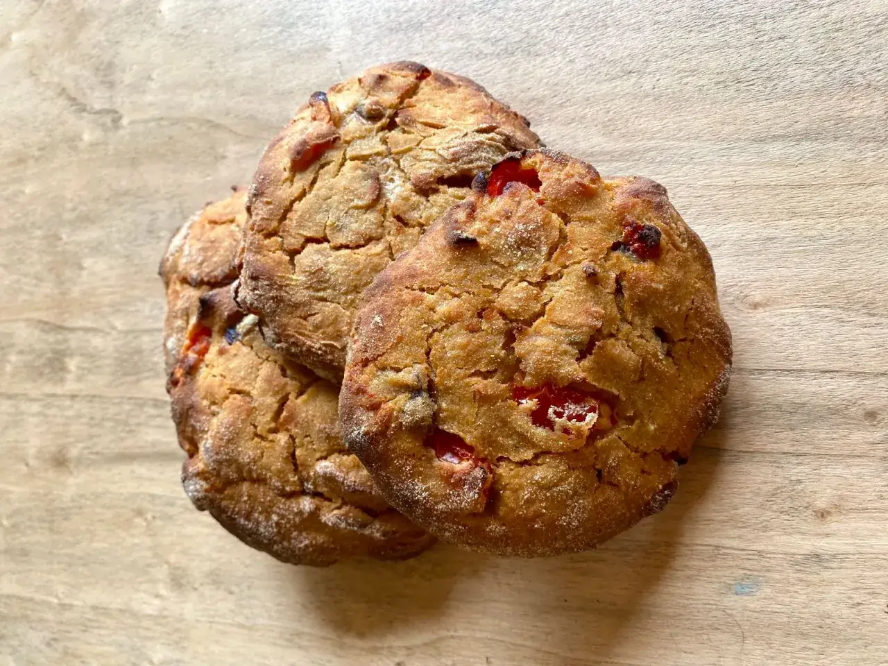 Tre rustici pane e pomodoro campi salentina, dorati e fragranti, su un tagliere di legno.