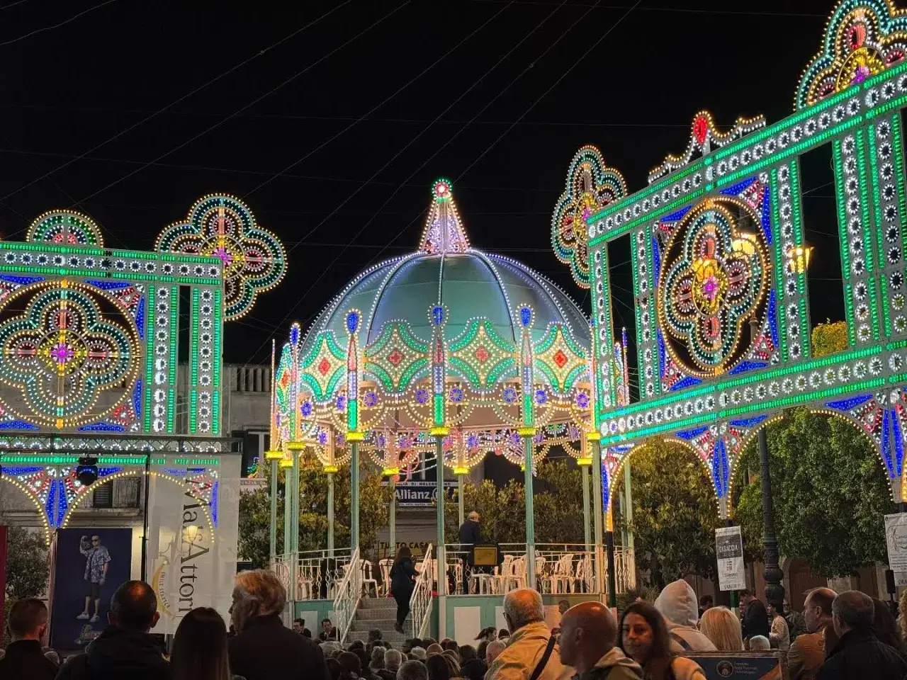 Luci scintillanti illuminano un palco e una folla, creando un'atmosfera magica per le feste e sagre oggi.