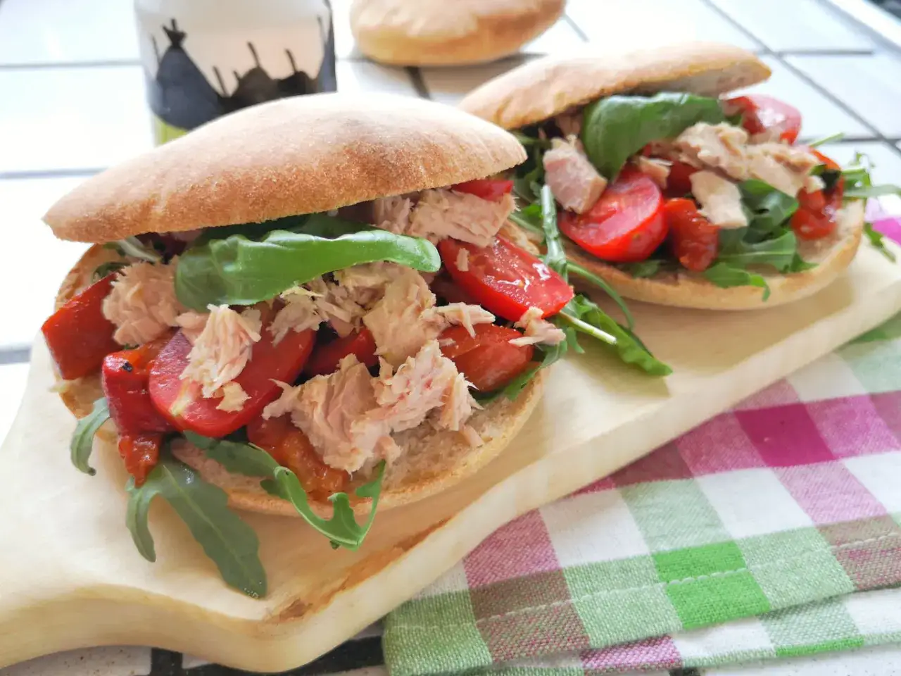 Due puccie salentine farcite con tonno, pomodorini e rucola. Un'idea fresca su come condire la puccia salentina per un pranzo veloce.