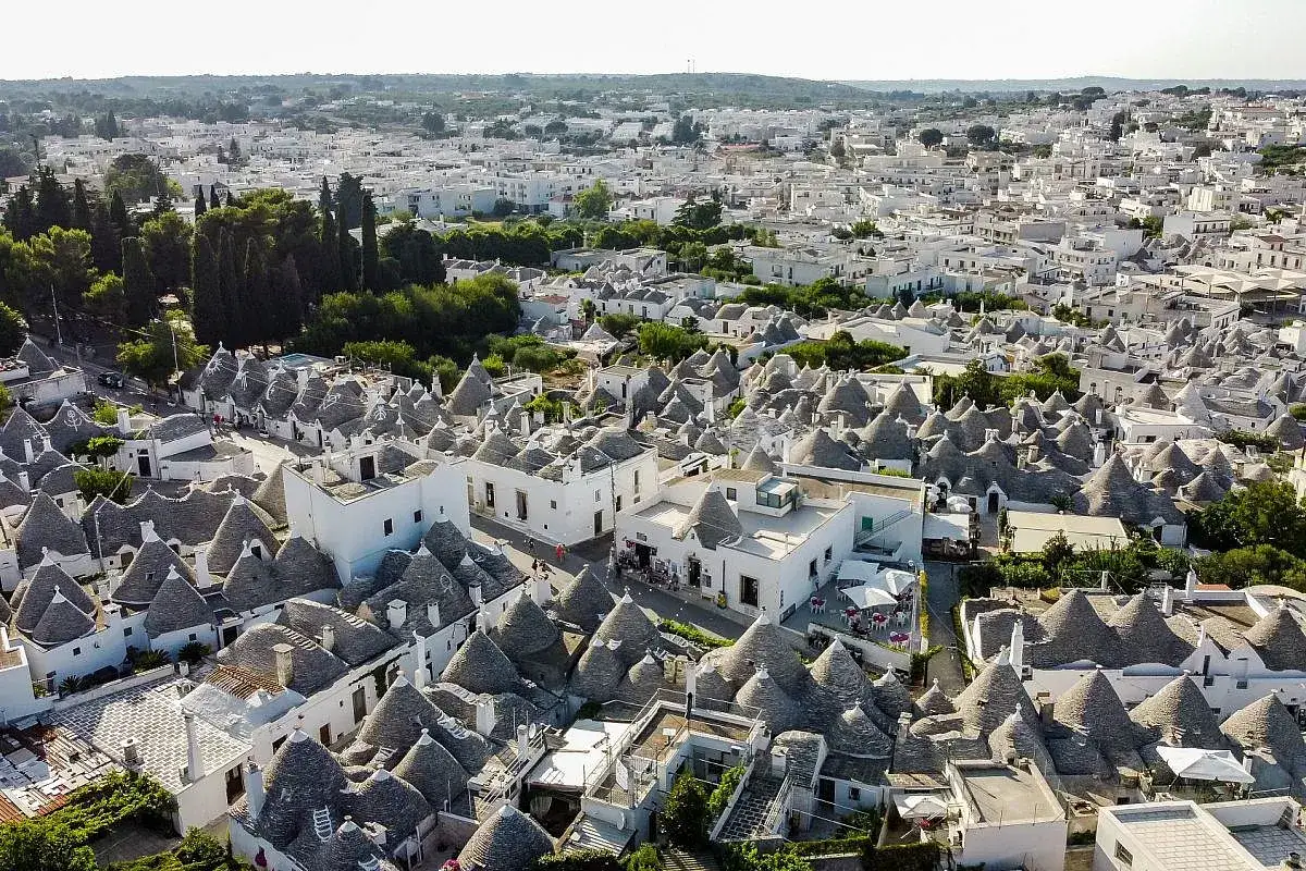 Un panorama di trulli bianchi con tetti conici, un'icona di cosa vedere in Puglia. Un paesaggio unico e affascinante.