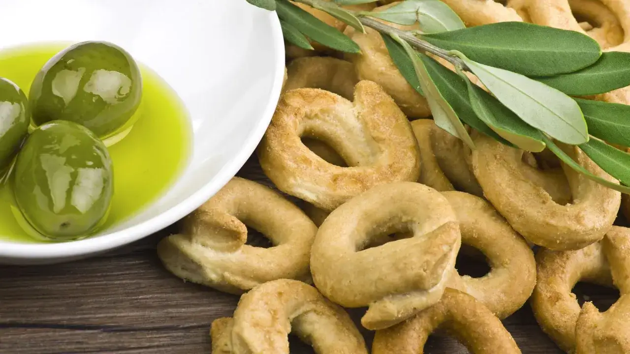 Taralli e olive verdi in olio, un assaggio dei contorni pugliesi con un rametto di ulivo.