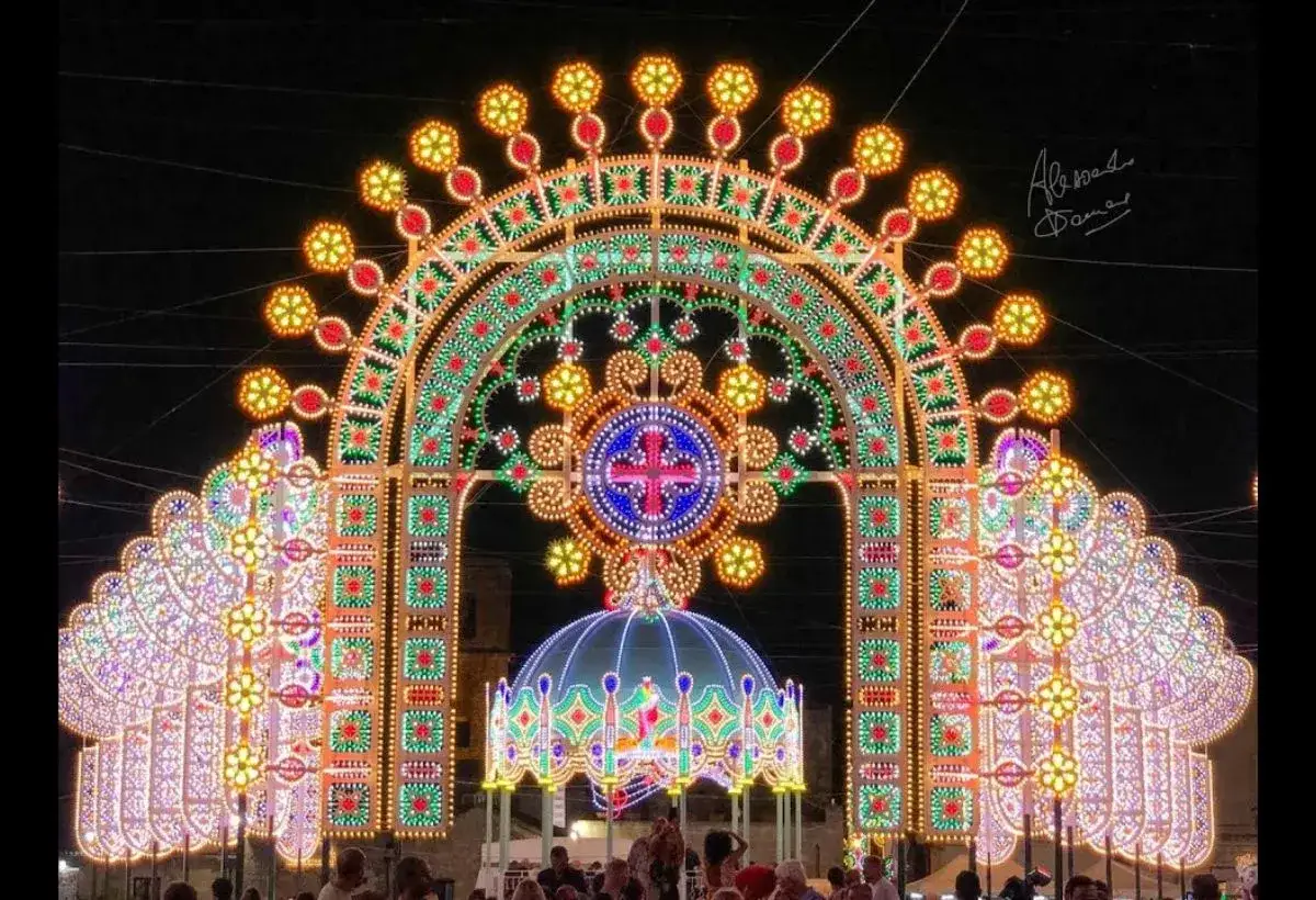 Un imponente arco di luci illumina la notte, un'installazione che fa pensare a che feste ci sono a novembre, con decorazioni elaborate e colorate.