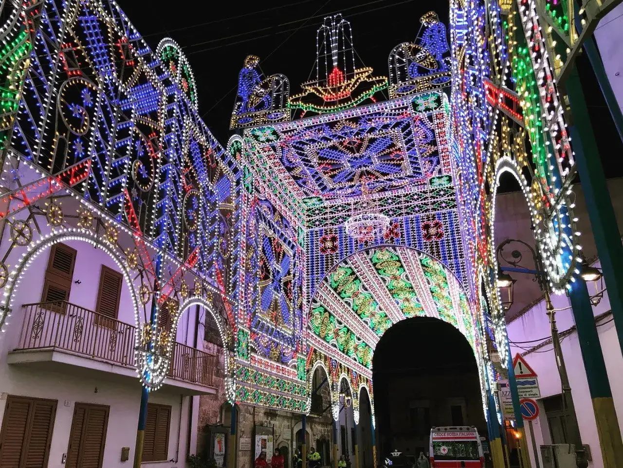 Un'imponente struttura di luci colorate illumina una strada di notte, creando un'atmosfera magica per una festa a diso.