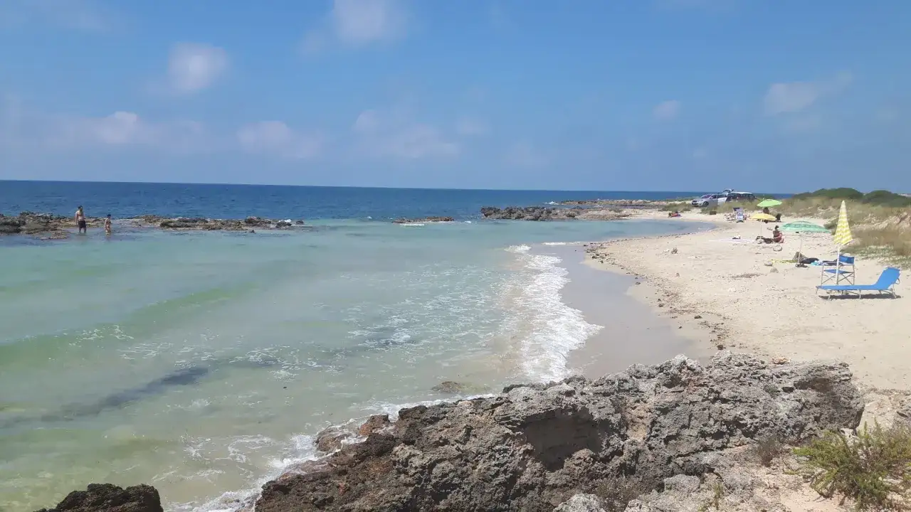 Spiaggia calette di Salve con acqua cristallina, rocce e bagnanti che si godono il sole.