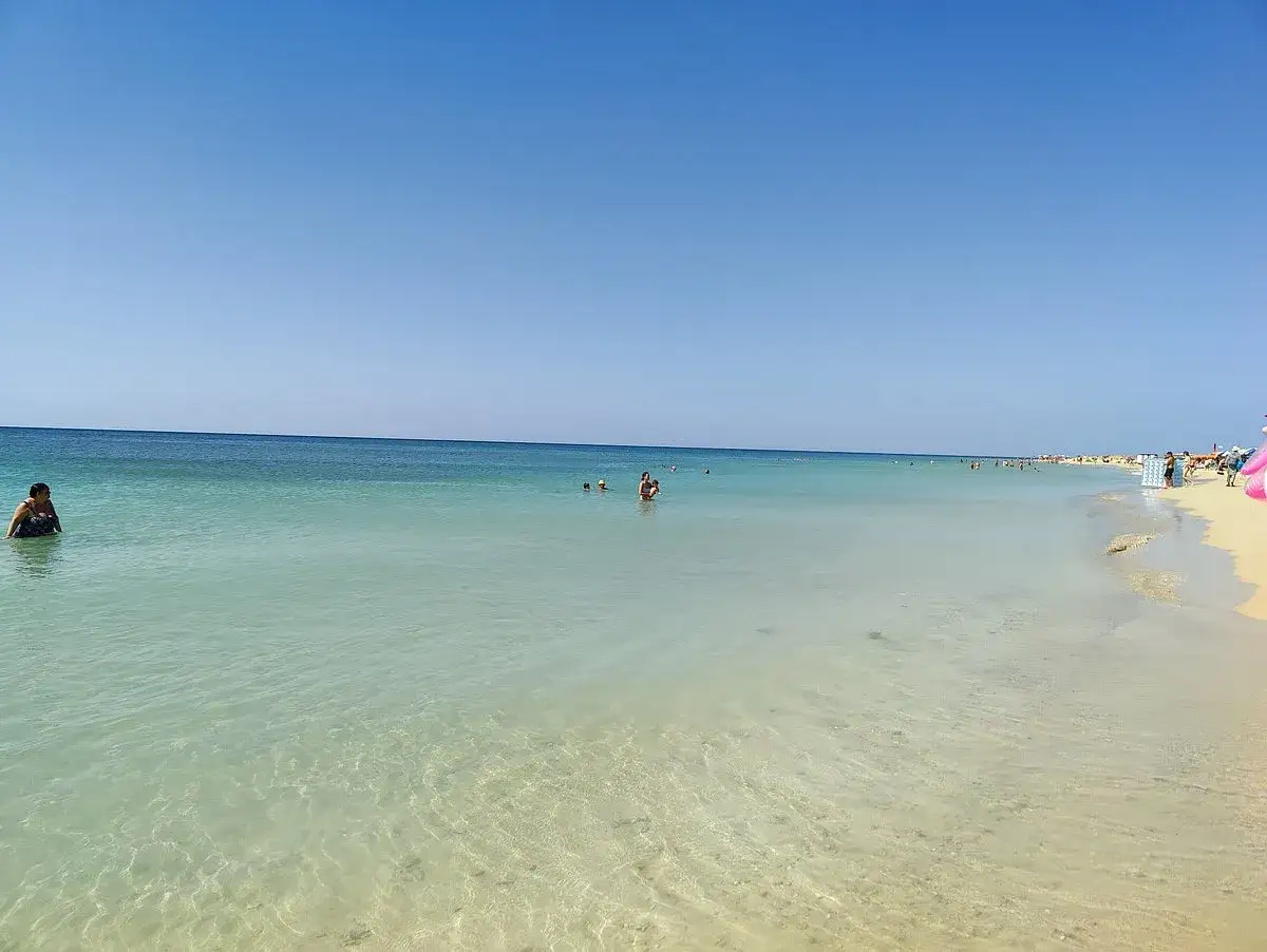 Spiaggia di Torre Pali, Lido Marini, con acque cristalline e gente che si gode il sole.