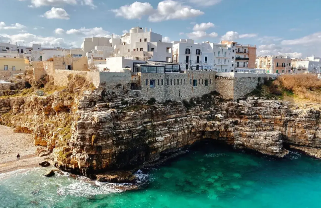 Scogliere mozzafiato e case bianche a picco sul mare turchese, un'immagine iconica della Puglia da visitare.