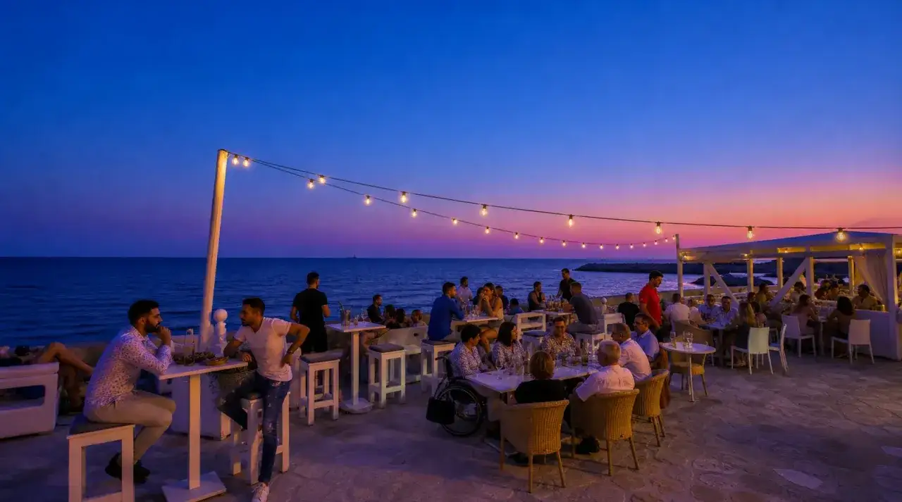Serata di Gallipoli movida con luci soffuse e gente che si gode il tramonto sul mare.