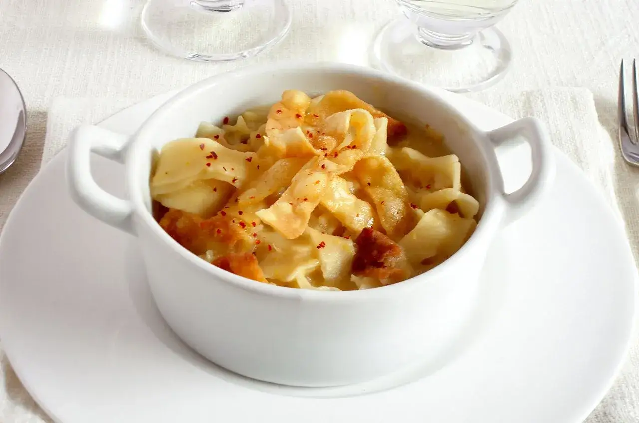 Pasticcio di pasta, un classico delle ricette leccesi, servito in una ciotola bianca con una spolverata di peperoncino.
