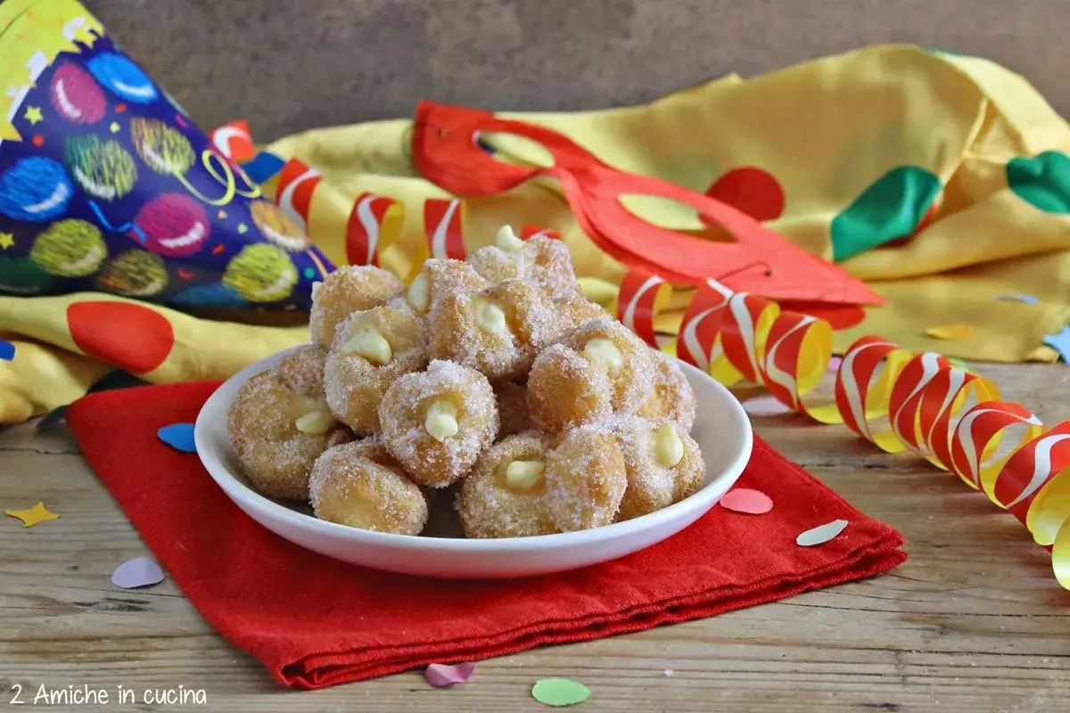 Dolci fritti ripieni di crema, cosparsi di zucchero, pronti per il Carnevale. Un assaggio di sanguinaccio pugliese tra maschere e coriandoli.