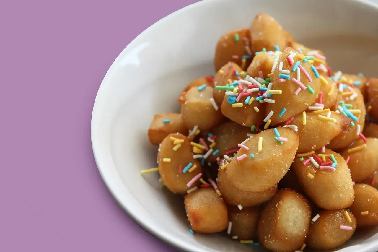 Un piatto di dolci tipici pugliesi, piccole palline dorate fritte e cosparse di zuccherini colorati.