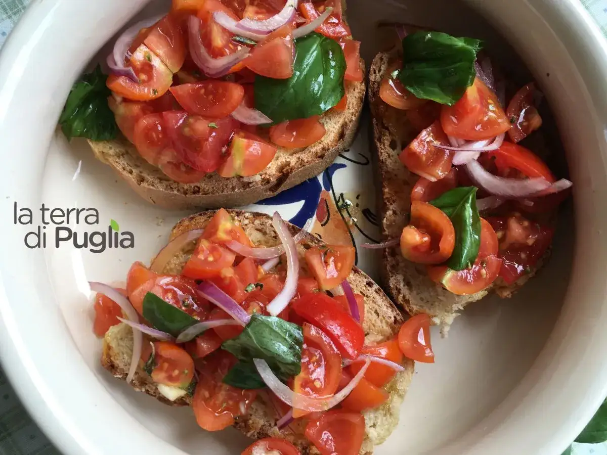 Bruschette con pomodoro fresco, cipolla rossa e basilico, un classico degli antipasti tipici pugliesi.