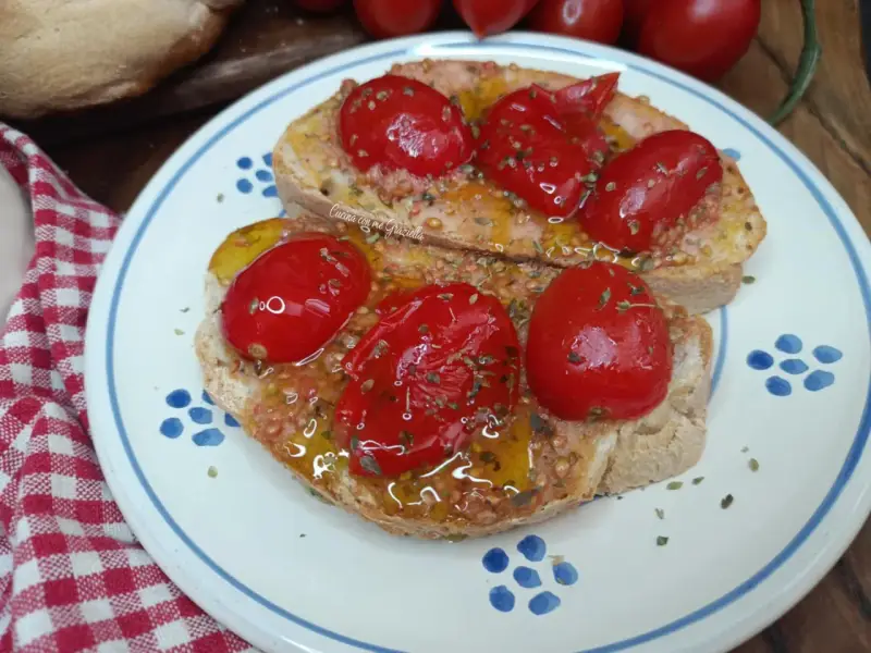 Pane e pomodoro, un assaggio dei campi salentini. Bruschette condite con pomodorini freschi, olio d'oliva e origano, su un piatto decorato.